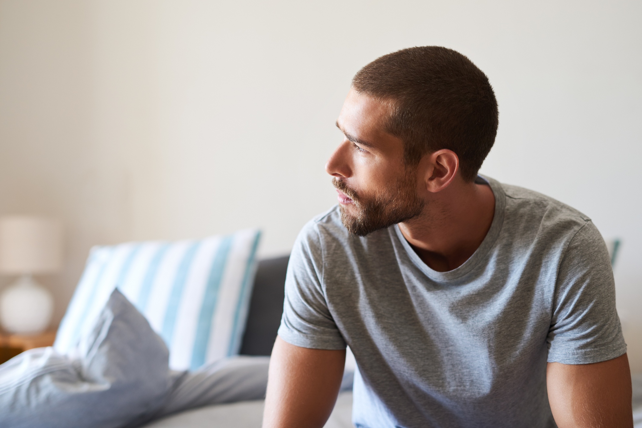 Shot of a handsome young man looking thoughtful in his bedroom at home